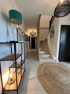 Ein Flur mit Treppe, einer weißen Pferdeskulptur, gerahmten Bildern, einem gewebten Korb und einem Webteppich.
