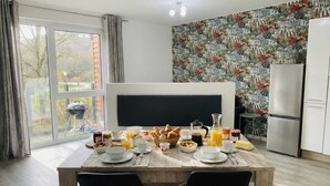 Uma sala de jantar com arrumação para o pequeno-almoço, uma janela grande e um papel de parede estampado.