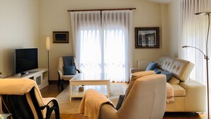A living room with a sofa, armchair, TV, and a table. - Holiday Home 'La Marina' with Sea View, Private Terrace and Wi-Fi (Barro)