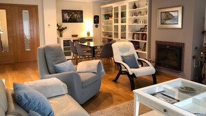 A living room with a fireplace, a dining area, and a bookshelf. - Holiday Home 'La Marina' with Sea View, Private Terrace and Wi-Fi (Barro)