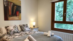 A bedroom with a bed, pillows, a nightstand with a lamp, and a window with a view of trees. - Holiday Home 'La Marina' with Sea View, Private Terrace and Wi-Fi (Barro)
