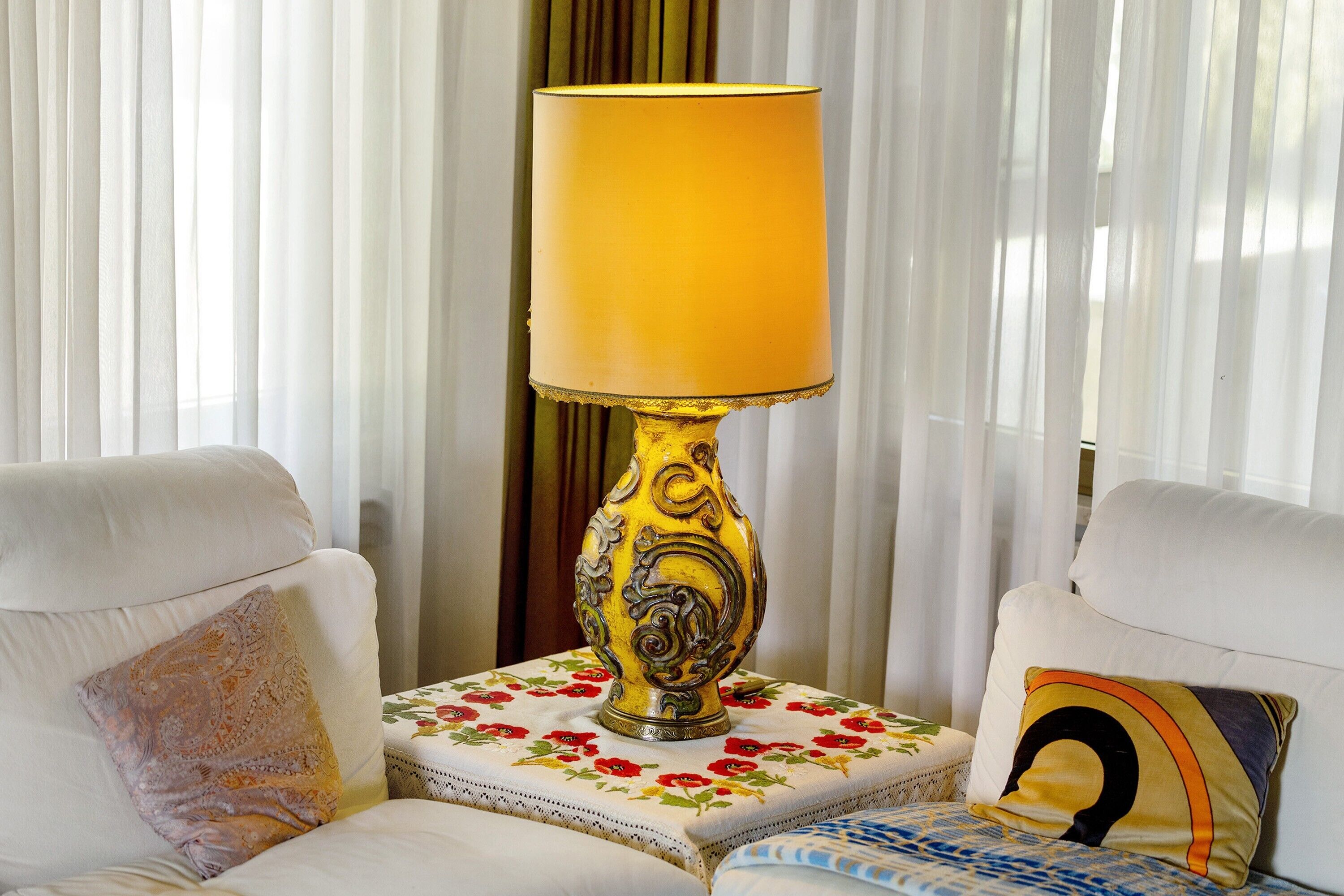 Une pièce avec une lampe de table, un canapé et un coussin orné d’un motif cachemire.