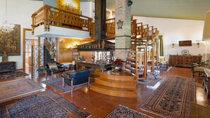 Um interior espaçoso com teto alto, escadaria central e lareira.