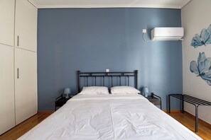 Ein Schlafzimmer mit Bett, Nachttisch, Wand-Klimaanlage und Wand mit Blumenmuster.