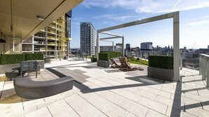A rooftop terrace with outdoor seating, a pergola, and a view of the city skyline. - Anaconda Cut - Campus Accommodation (Salford)