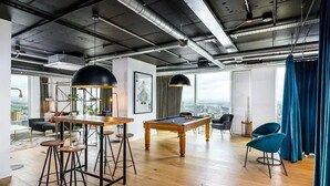 A modern interior with a pool table, bar stools, and a view of the city. - Anaconda Cut - Campus Accommodation (Salford)