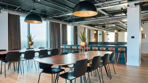 A modern conference room with a large wooden table, black chairs, and pendant lighting. - Anaconda Cut - Campus Accommodation (Salford)