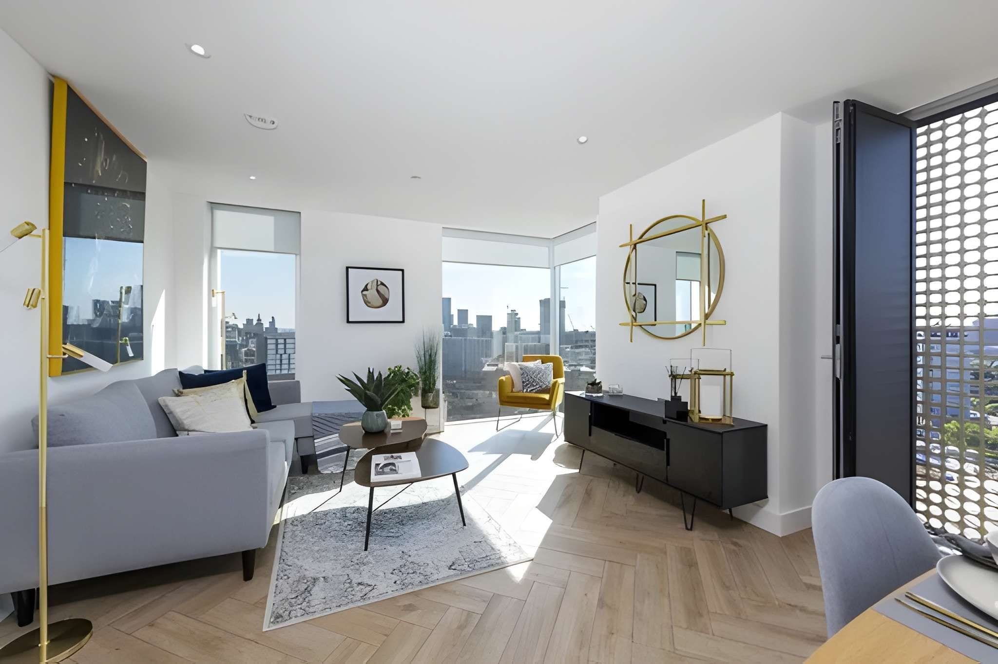 A modern living room with a sofa, coffee table, and a city view through large windows.