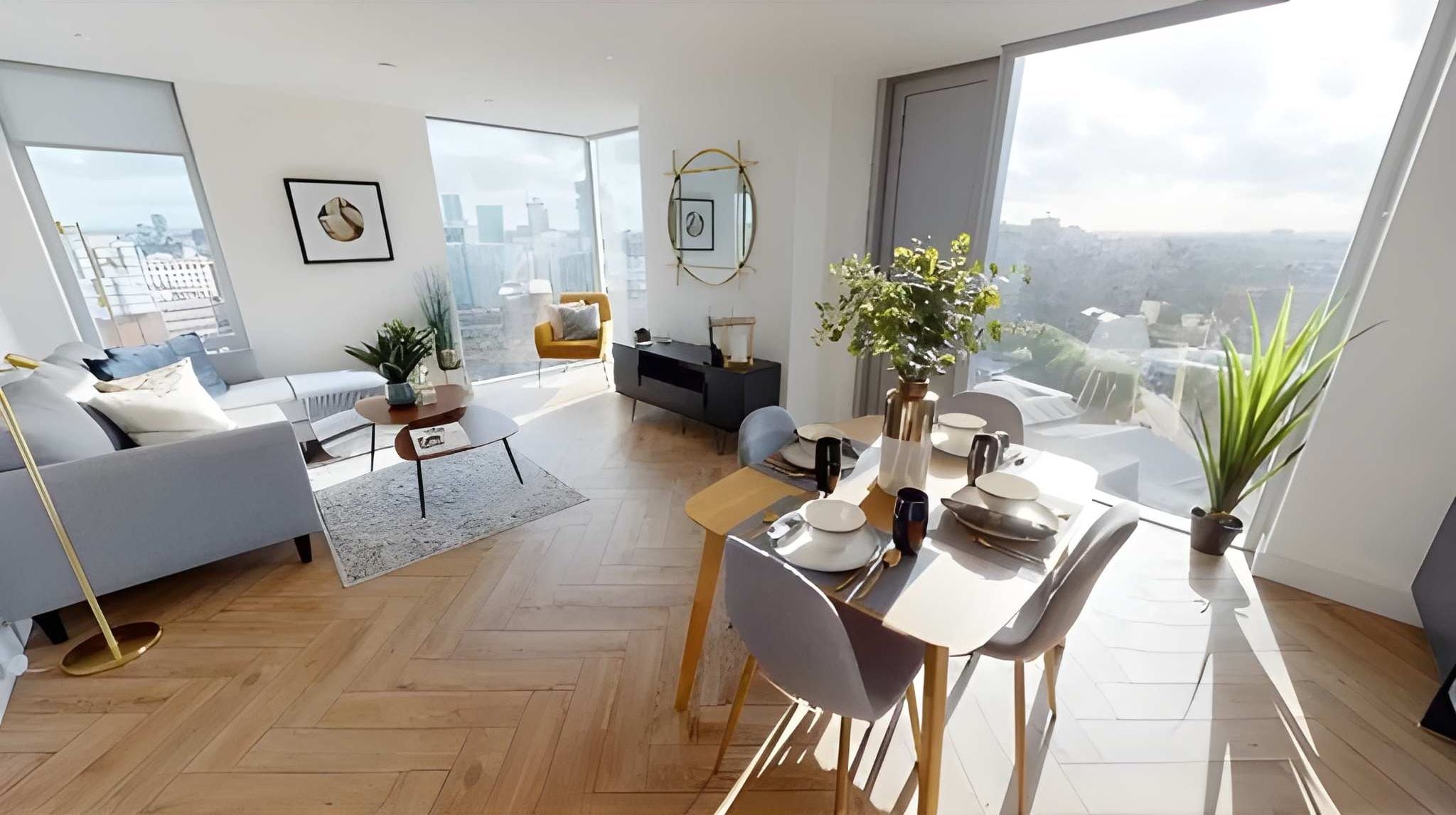 A modern living room with a dining area, large windows, and a city view.