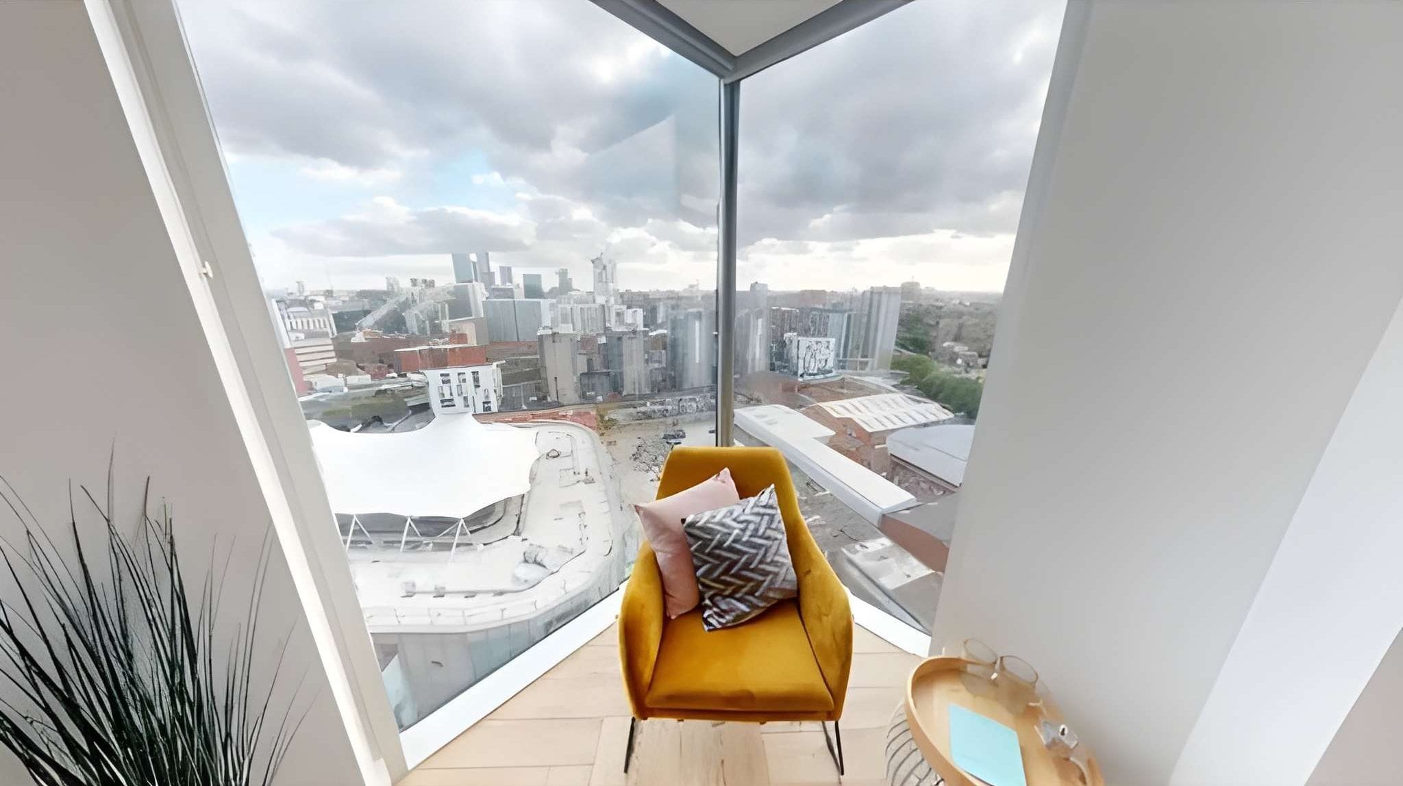 A modern room with a large window, a yellow chair, and a view of a cityscape.