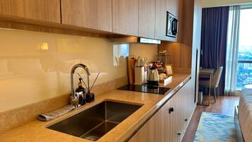 Habitación de hotel con cocina, mesa de comedor y vista a la ciudad.