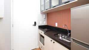 A compact kitchen with a built-in oven, a stainless steel sink, and a refrigerator. - Blend (São Paulo)