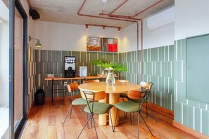 A conference room with a round table, chairs, a coffee machine, and a plant. - Blend (São Paulo)