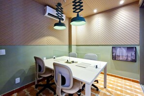A conference room with a white table, four chairs, a ceiling-mounted air conditioner, and a cityscape picture on the wall. - Blend (São Paulo)