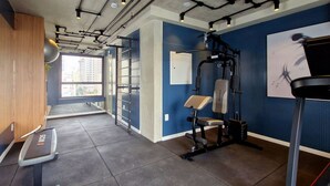 A gym with exercise equipment, a treadmill, and a window with a city view. - Blend (São Paulo)