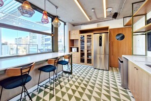 A modern kitchen with a large window, bar stools, and a stainless steel refrigerator. - Blend (São Paulo)