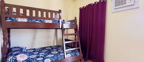 A bunk bed with a floral-patterned mattress, a ladder, and a wall-mounted air conditioning unit.