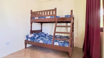 A bunk bed in a room with wooden flooring and a ceiling light fixture.