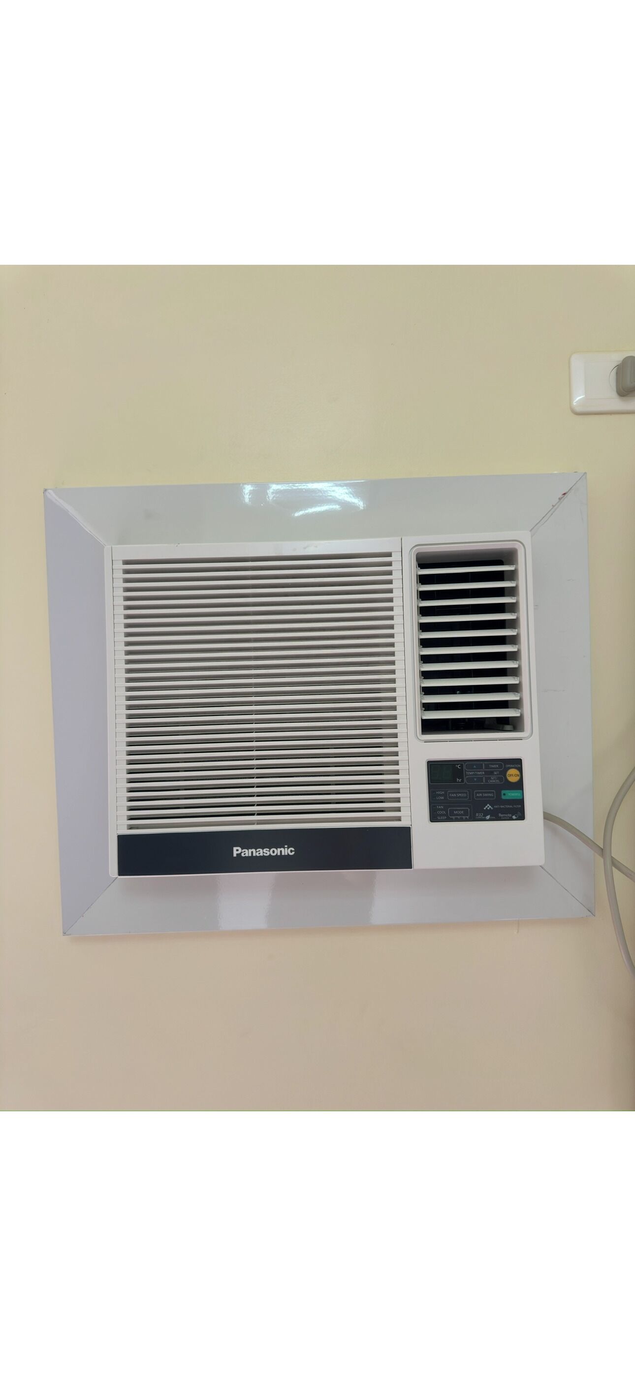 A white Panasonic air conditioner mounted on a wall with a control panel on the right side.