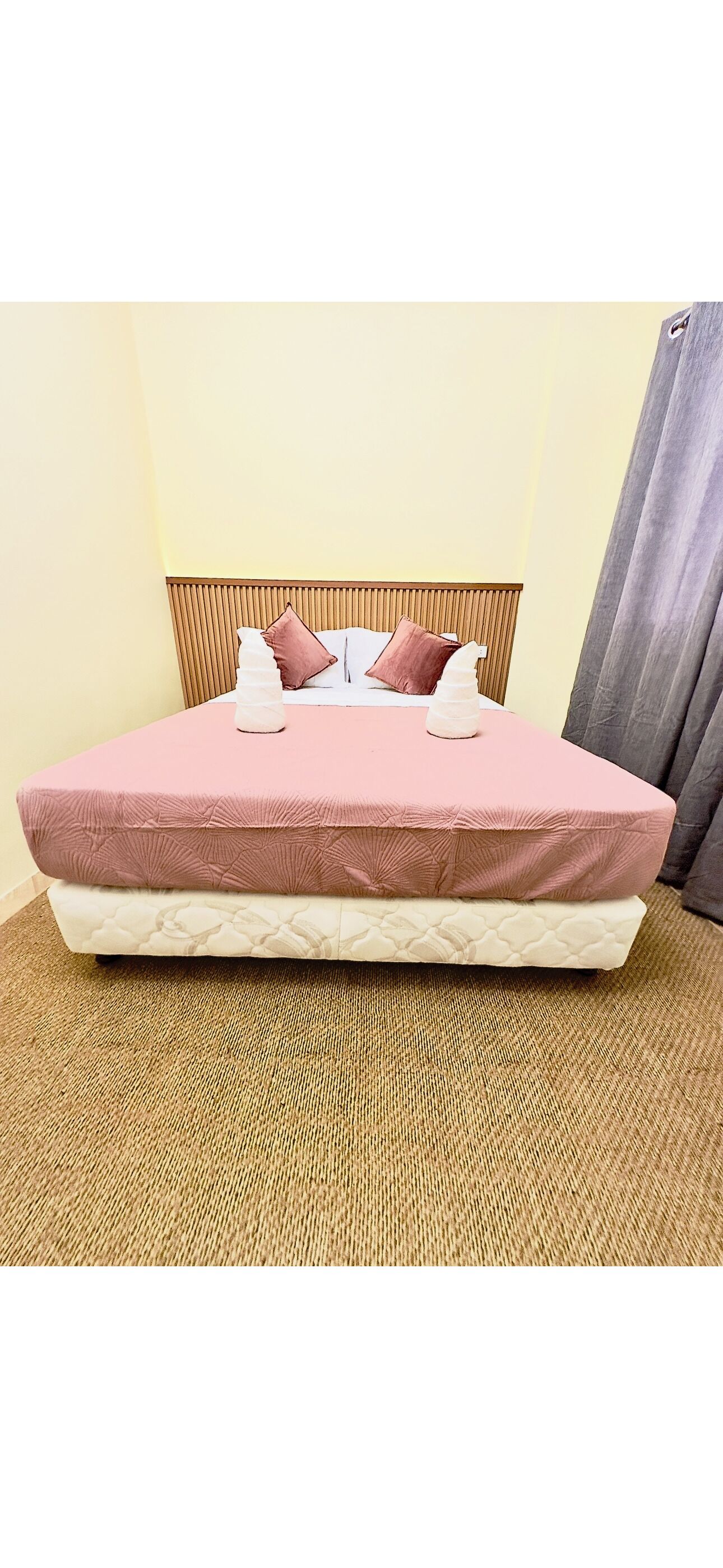 Un letto con una testiera in legno, due cuscini e un materasso rosa.