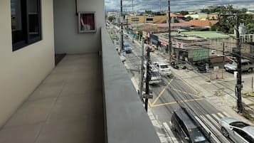 A balcony with a view of a busy street, a building with a sign, and a clear sky.