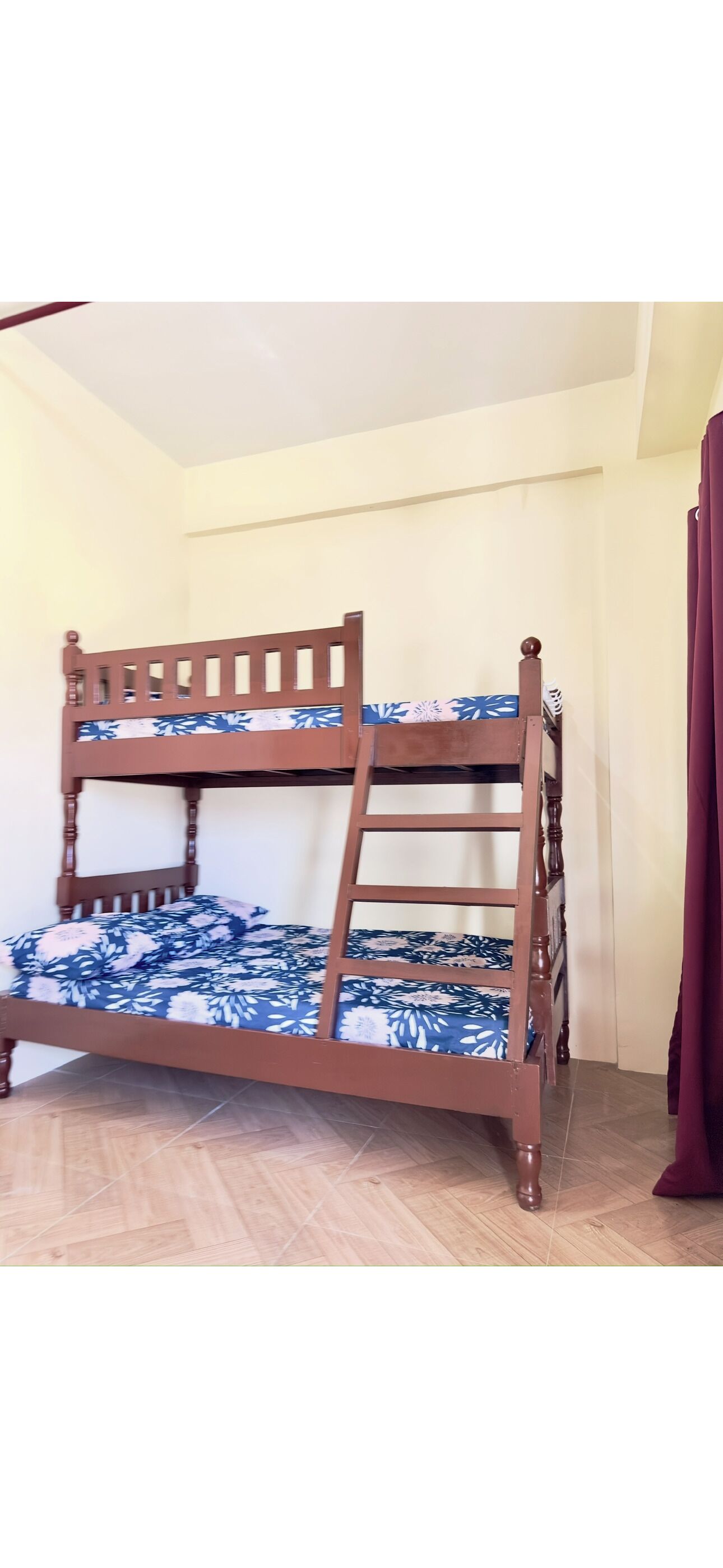 Un lit superposé avec un matelas à motifs floraux, une tête de lit en bois et une échelle.