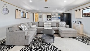 A modern living room with a sectional sofa, a round coffee table, and a zebra-patterned rug. - Zebra Ranch 150 Guest Venue Lodging Mtn Vu Farm (Prescott)