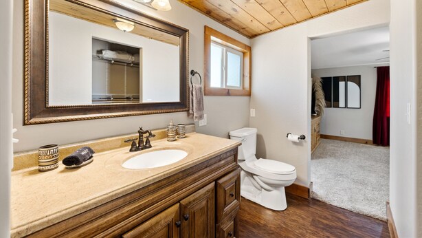 A bathroom with a wooden vanity, a large mirror, a toilet, and a window. - Zebra Ranch 150 Guest Venue Lodging Mtn Vu Farm (Prescott)