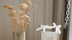 A glass vase with dried flowers, a sign reading 'Cards & Gifts,' and a metal basket with a spoon. - Zebra Ranch 150 Guest Venue Lodging Mtn Vu Farm (Prescott)