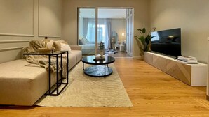 Uma sala de estar moderna com sofá, mesa de centro, televisão e vista para o exterior.