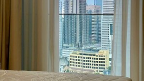 Quarto com uma janela grande, cama e cortinas.