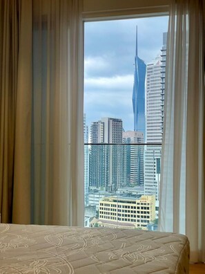Un dormitorio con un ventanal grande, una cama y cortinas.
