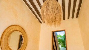 A room with a circular mirror, a hanging light fixture, and a doorway leading to an outdoor area.