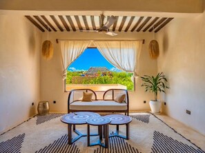 Une pièce avec un lit, une table, une plante en pot et une fenêtre donnant sur un beau paysage.