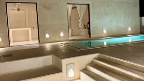 A modern pool area with steps leading to a pool, a ceiling fan, and a bathroom with a curtain.