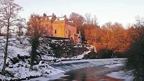 Ein schlösserähnliches Gebäude mit einem Fluss davor.