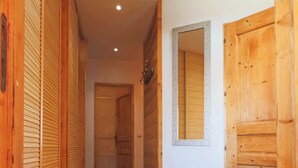 A hallway with wooden doors, a mirror, and a tiled floor. - Chalet apartment for rent with south-facing terrace and private sauna (saint francois longchamp)