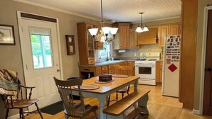 Una cocina con armarios de madera, una isla central, una mesa de comedor con sillas y un refrigerador.