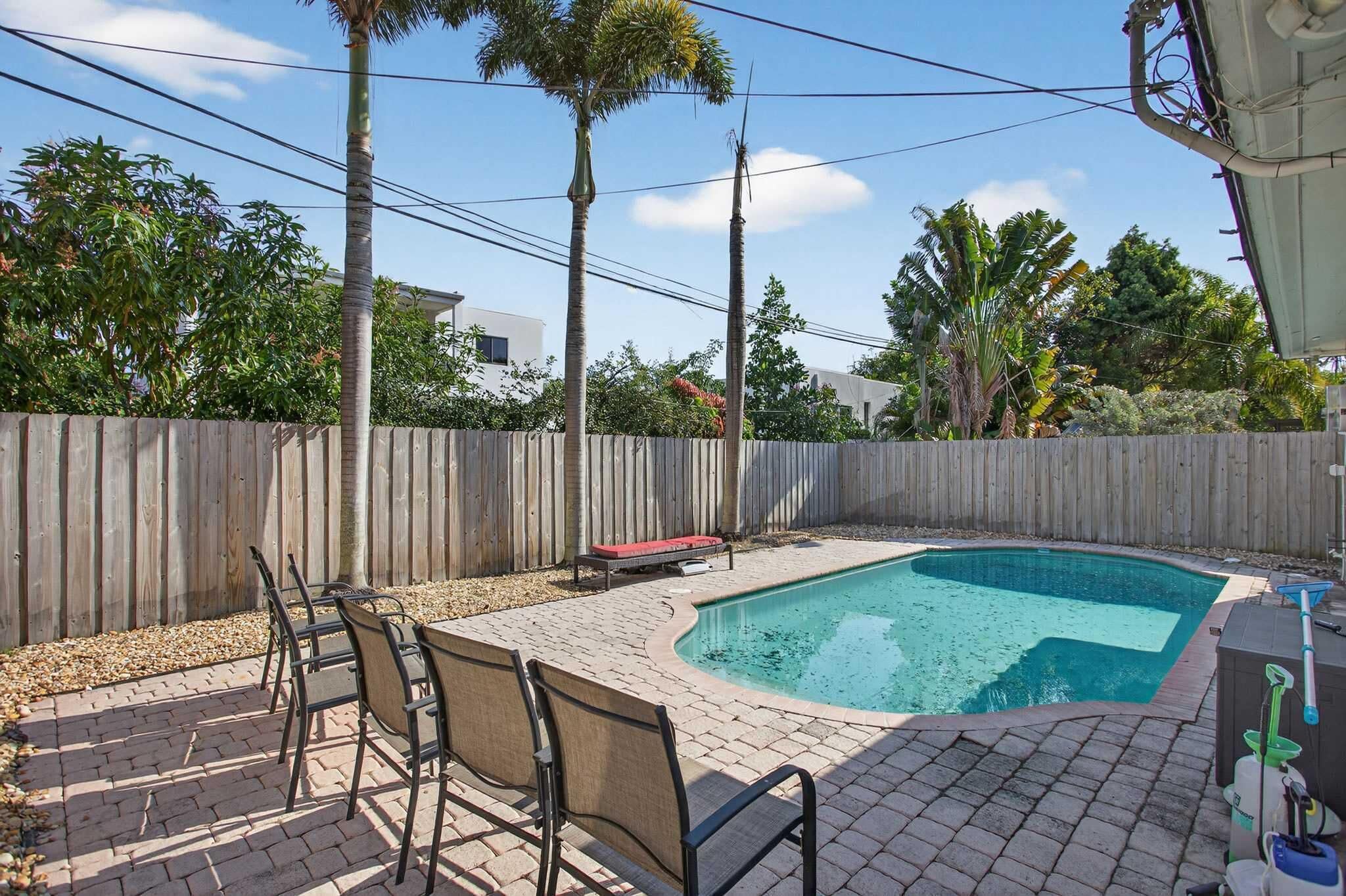 A backyard with a swimming pool, patio furniture, and a wooden fence.