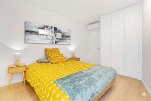 A bedroom with a bed, bedside tables, a wardrobe, and a wall-mounted abstract painting.