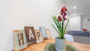 Un tavolo di legno con una pianta in vaso, un sottopiatti intrecciato e lettere di legno rustico che formano la parola 'HAPPY'.