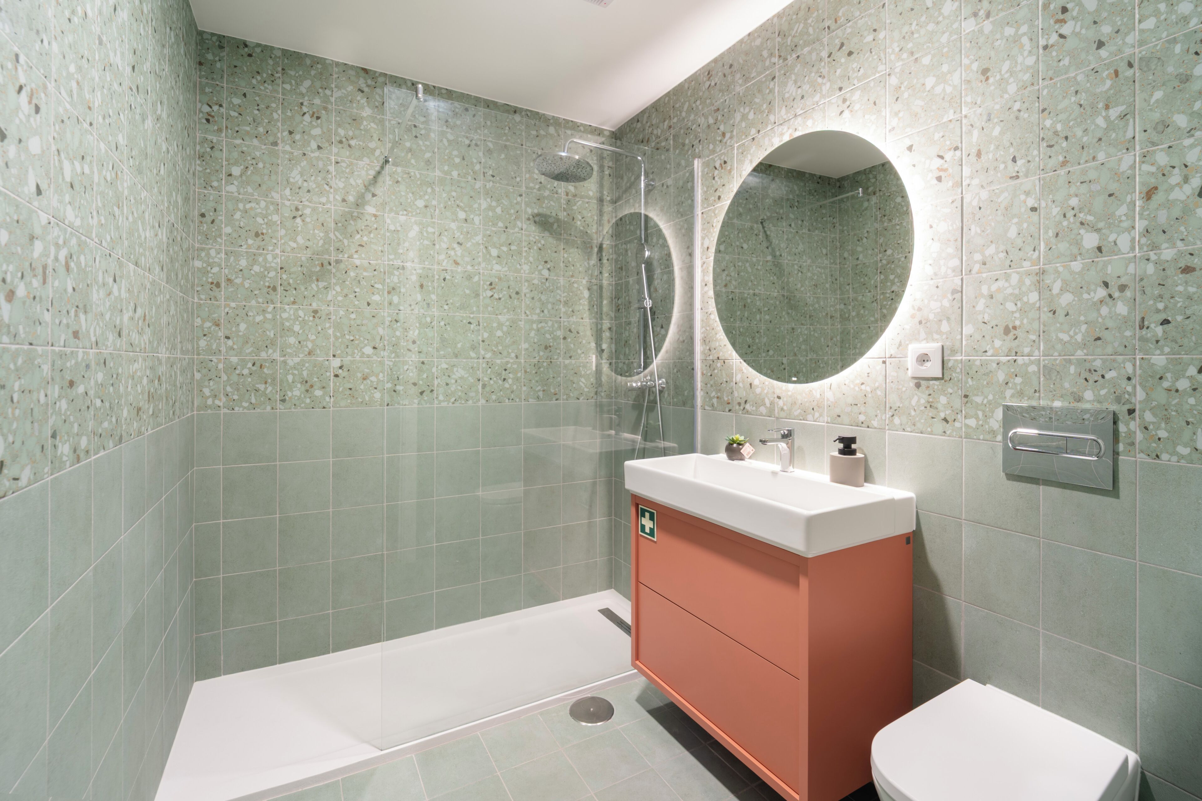 Un baño con ducha, inodoro y tocador con espejo.