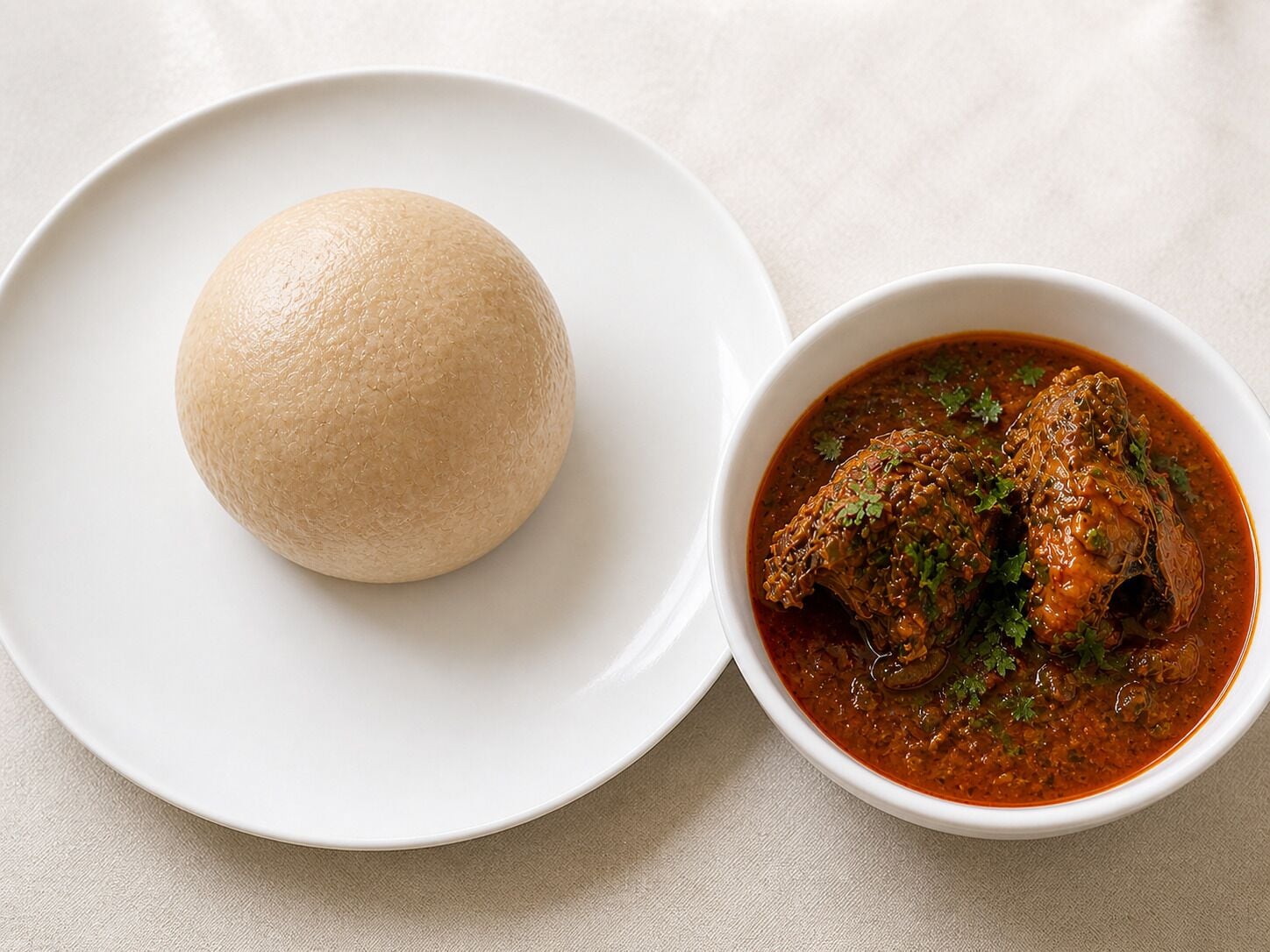 Un plato con un alimento redondo y un bol de estofado con carne y hierbas.