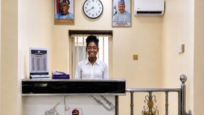 A reception desk with a clock, framed pictures, and a 'Please No Smoking' sign. - The Whale Inn (Kaduna)