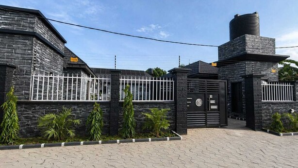 A modern building with a stone facade, a gated entrance, and a water tank on the roof. - The Whale Inn (Kaduna)