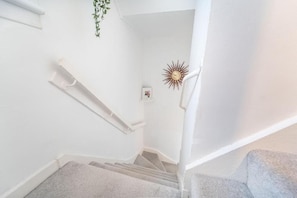 A staircase with a handrail, carpeted steps, and a wall-mounted clock. - Highland Holiday Home in Fort William & Ben Nevis | Sleeps 4 (Caol)