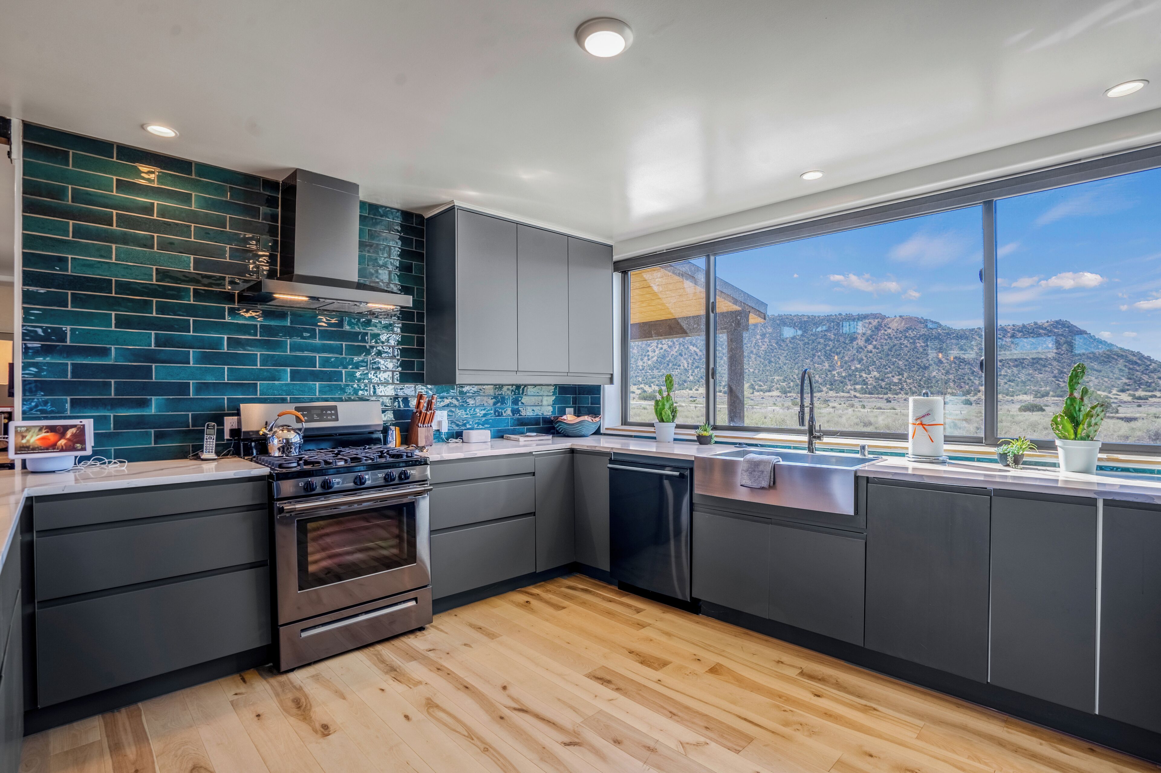 A modern kitchen with a large window, a stove, and a dishwasher.