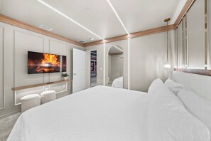 A modern bedroom with a large bed, a flat-screen TV mounted on the wall, and a hallway leading to a bathroom. - 10BR house with private pool in clermont (Clermont)