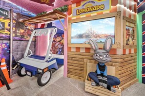 A lemonade stand with a cartoon rabbit mascot, a lemonade sign, and a view of a cityscape through a window. - 10BR house sleeps 26 with private pool (Clermont)