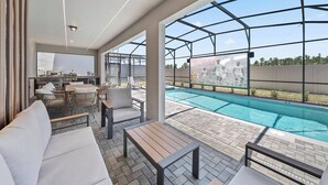 A poolside area with a seating arrangement, a pool, and a view of a sports event. - 10BR house sleeps 26 with private pool (Clermont)